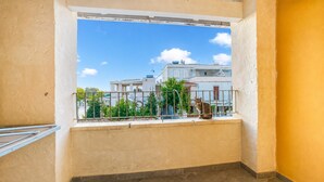 Un balcon donnant sur des immeubles, avec une balustrade et un chat.