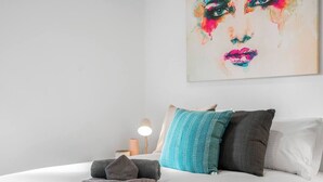 Una cama bien hecha con almohadas, una lámpara de noche y una toalla sobre la cama.