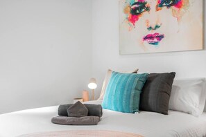 Ein ordentlich gemachtes Bett mit Kissen, einer Nachttischlampe und einem Handtuch.