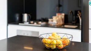 Una cocina con una encimera, un cuenco de fruta y una cafetera al fondo.