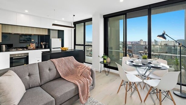 Un apartamento moderno con cocina, comedor y ventanas amplias que ofrecen vistas a la ciudad.