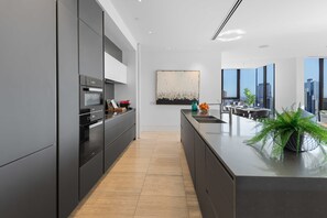 Eine moderne Küche mit einer zentralen Kochinsel, integrierten Geräten und großen Fenstern mit Blick auf die Stadt.
