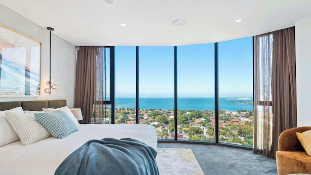 Una camera da letto con un letto grande, vista mare e sullo skyline della città.