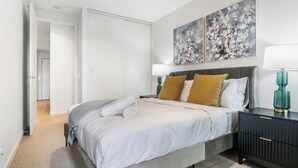 Ein modernes Schlafzimmer mit Bett, Nachttischen und Bildern an der Wand.