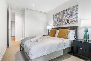 Ein modernes Schlafzimmer mit Bett, Nachttischen und Bildern an der Wand.
