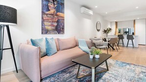 Ein modernes Wohnzimmer mit einer Couch, einem Couchtisch und einem Gemälde an der Wand.