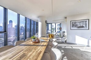 Ein moderner Arbeitsraum mit einem großen Holztisch, bequemen Sitzgelegenheiten und großen Fenstern mit Blick auf die Stadt.