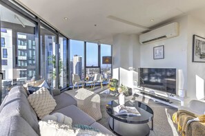 Ein modernes Wohnzimmer mit einer großen Couch, einem Couchtisch und einem Flachbildfernseher.