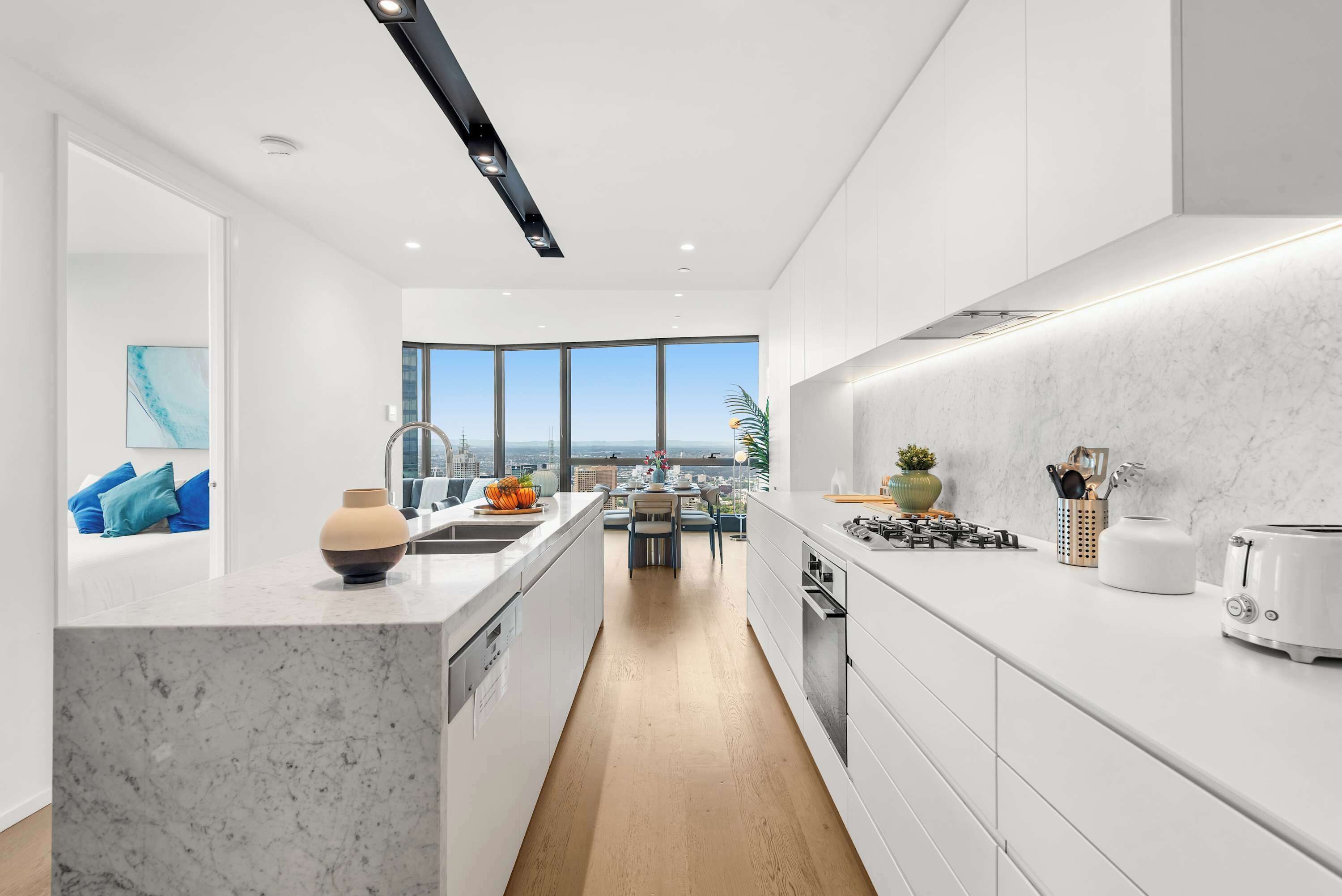 Una cocina moderna con una isla central, armarios blancos y vistas al exterior.