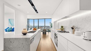 Una cocina moderna con una isla central, armarios blancos y vistas al exterior.