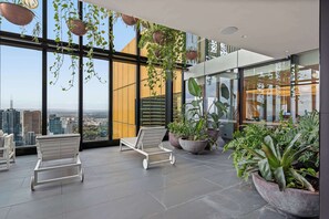 Ein moderner Lounge-Bereich mit großen Fenstern, Topfpflanzen und weißen Liegesesseln.