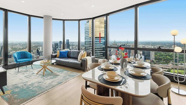 Un comedor moderno con vistas a la ciudad, un sofá, un sillón azul y una mesa lista para comer.