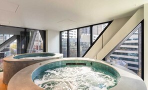 Ein modernes Hotelzimmer mit großem Fenster, Whirlpool und Blick auf die Stadt.