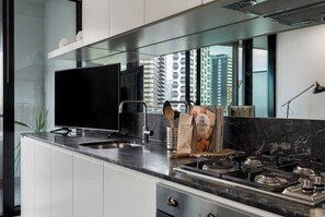 Eine moderne Küche mit Flachbildfernseher, Gasherd und Fenster mit Blick auf die Stadt.