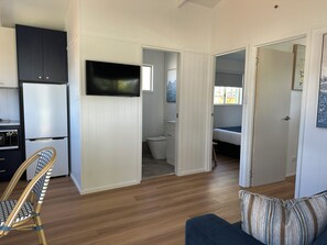 A compact living space with a kitchenette, a television, a bed, and a bathroom.