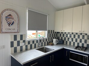 A kitchen with a sink, a kettle, a toaster, and cabinets.