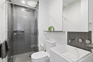 Une salle de bain moderne équipée d’une douche, de toilettes et d’une baignoire.