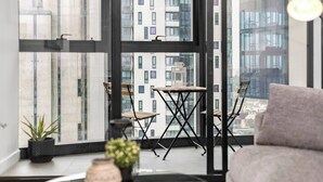 A modern balcony with a view of high-rise buildings, a small table, and two chairs. - Riley - Resort Living * Gym Sauna Pool Wi-Fi (Southbank)
