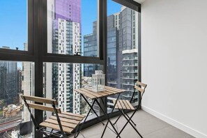 Une pièce avec une grande fenêtre, une table en bois et deux chaises.