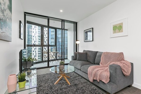 Un salon moderne avec un canapé gris, une table basse en verre et un tapis noir et blanc.