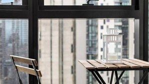 A view through a window with a table and a chair, a candle holder, and a building in the background. - Riley - Resort Living * Gym Sauna Pool Wi-Fi (Southbank)