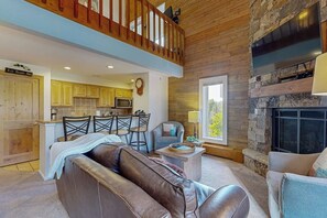 Ein geräumiges Wohnzimmer mit einer Ledersofa, einem Essbereich mit Stühlen, einer Küche mit Holzschränken und einem Kamin aus Stein.