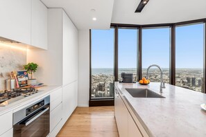 Eine moderne Küche mit Stadtblick, einem großen Fenster und einer Spüle mit Orangen.