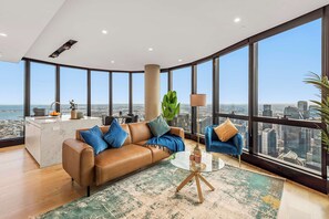 Ein modernes Wohnzimmer mit großem Fenster, einer Couch, einem Couchtisch und Blick auf die Stadt.