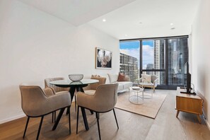 A modern living room with a dining area, large windows, and a city view. - Executive living in Melbourne's best location. (Southbank)