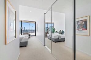 Ein modernes Hotelzimmer mit einem großen Bett, einem kleineren Bett, einem Balkon mit Blick und einem großen Fenster.
