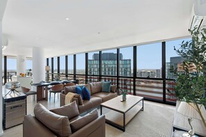 Ein geräumiger Wohnbereich mit großem Fenster, einer Couch, einem Couchtisch und einem Essbereich mit Stühlen und Tisch.
