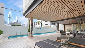 A rooftop pool area with lounge chairs, a pool, and a city skyline view. - Southbank stunner with parking views gym and pool! (South Melbourne)