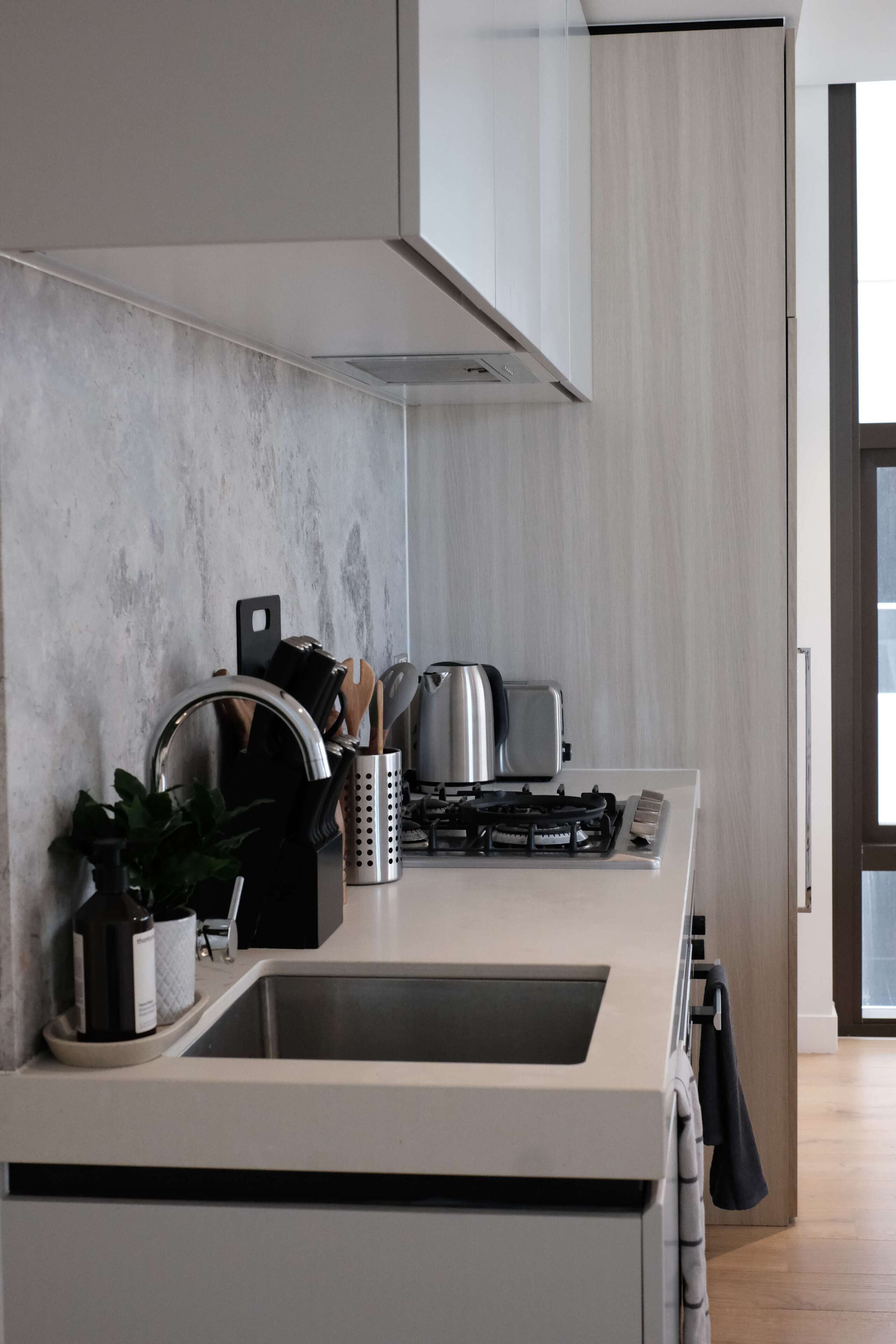 A modern kitchen with a stainless steel sink, a gas stove, and a range hood.