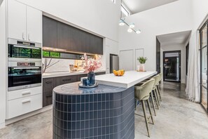 A modern kitchen with a central island, built-in appliances, and a dining area with bar stools.