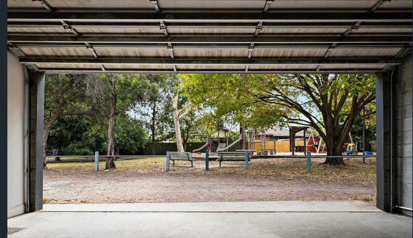 An outdoor area with a bench, trees, and playground equipment.