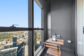A balcony with a view of a cityscape, a wooden bench, and a small table with a lamp. - Ultralux Southbank 3BD with jaw-dropping views (Southbank)