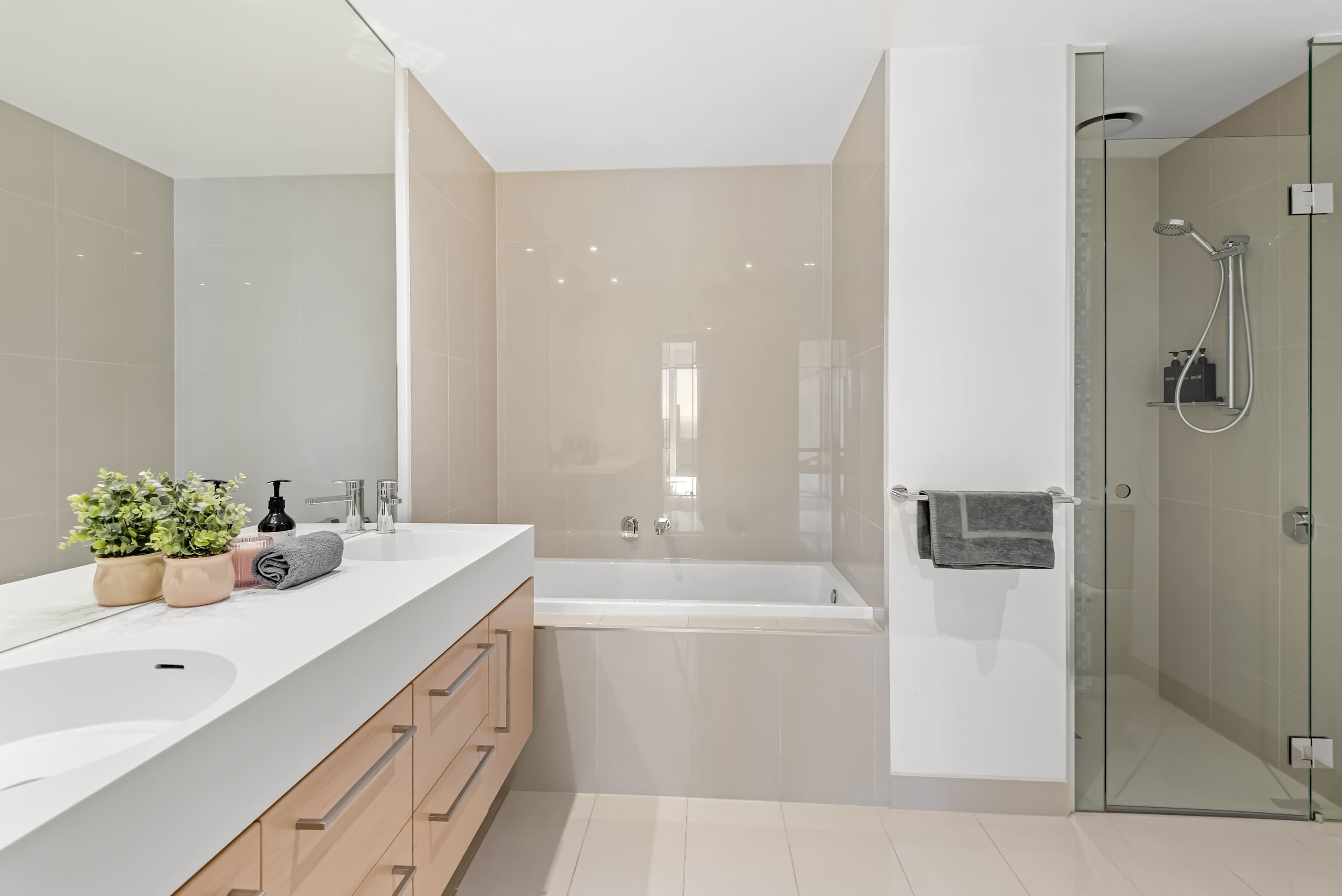 Une salle de bain moderne dotée d’une grande baignoire, d’une douche à parois de verre et d’un meuble-lavabo avec un évier et un miroir.