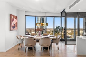 A dining area with a table set for four, large windows, and a city view. - Ultralux Southbank 3BD with jaw-dropping views (Southbank)