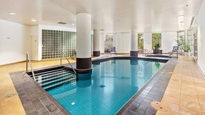 Una piscina interna con pavimento piastrellato, scaletta e parete piastrellata sullo sfondo.