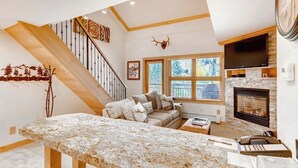 Una sala de estar con chimenea, un sofá, una mesa de centro y una escalera.