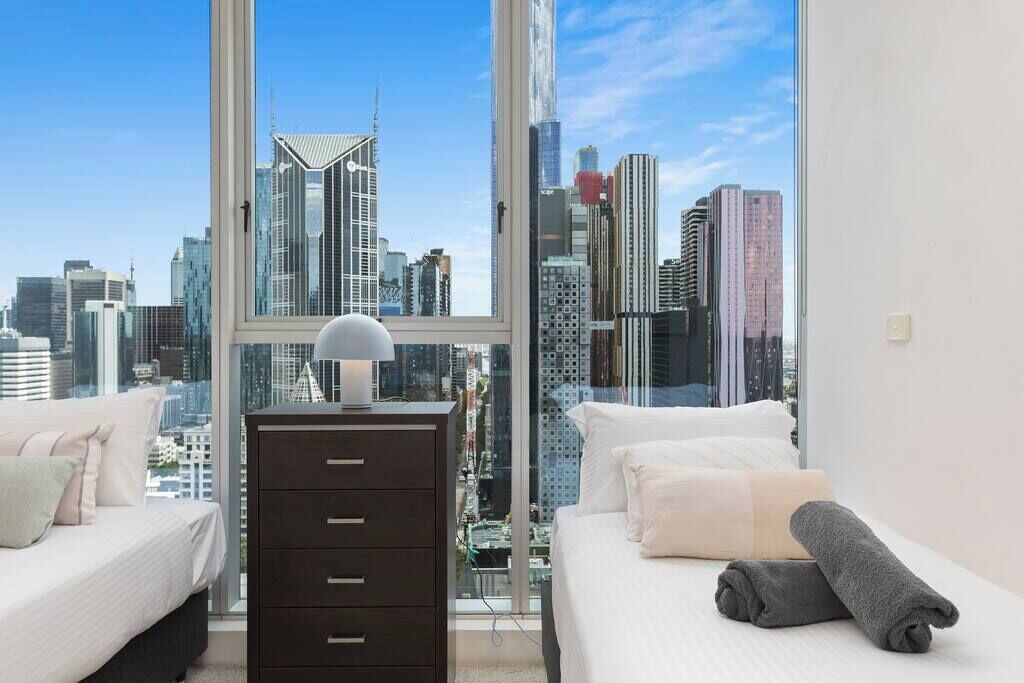 Ein Schlafzimmer mit Blick auf die Stadt, einem Schminktisch und zwei Betten.