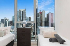 Ein Schlafzimmer mit Blick auf die Stadt, einem Schminktisch und zwei Betten.