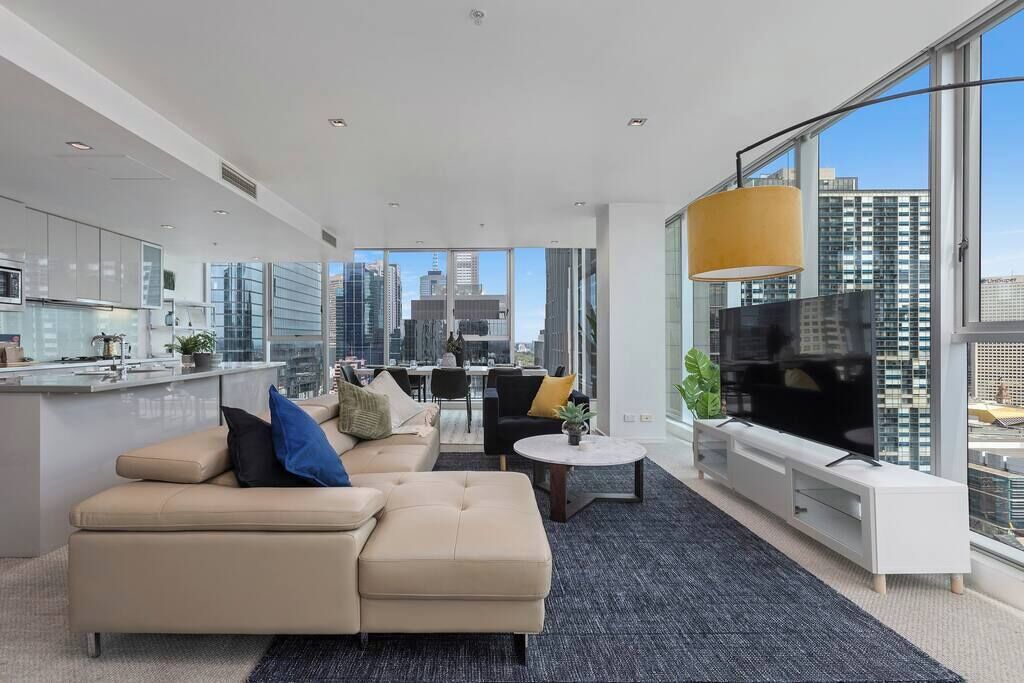 Een moderne woonkamer met een bank, televisie en uitzicht over de stad.