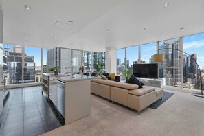 Ein modernes Wohnzimmer mit einer großen Couch, einem Fernseher und Blick auf die Stadt.