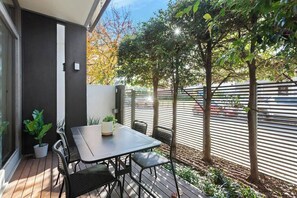 A patio with a table and chairs, surrounded by potted plants and trees. - Sia - Ultimate Executive Home with 4BDR and Parking (South Yarra)