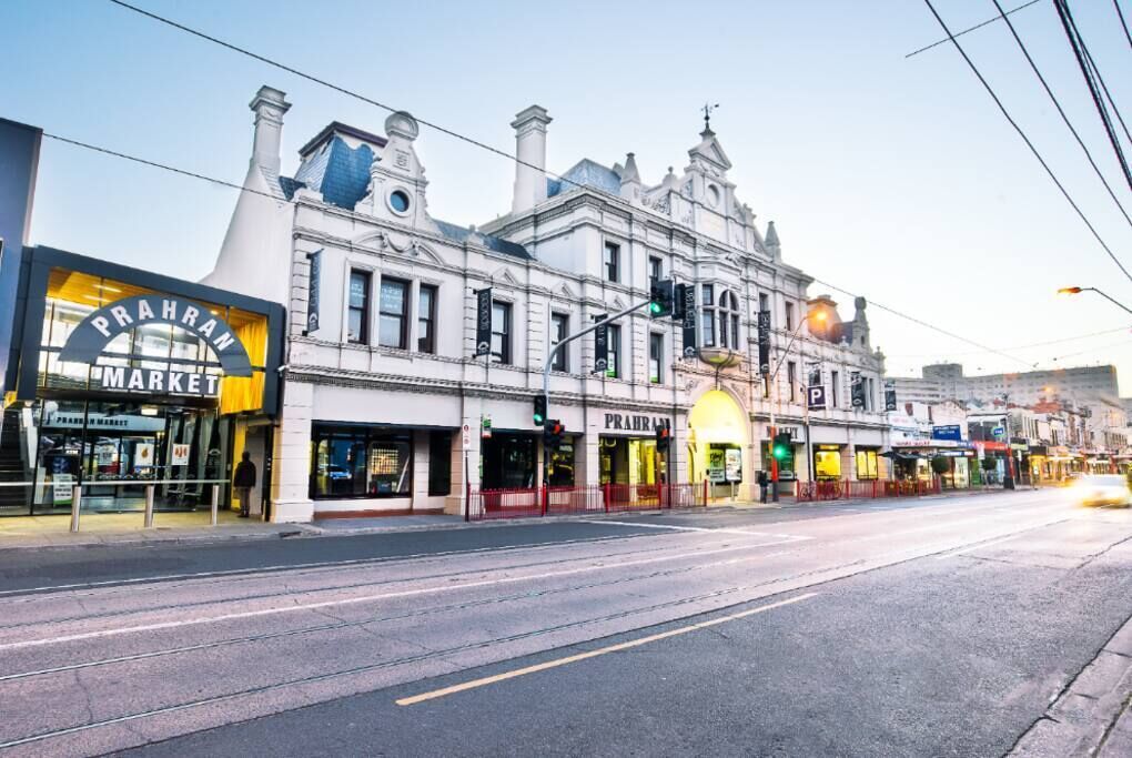 A street view with a building featuring a prominent 'Prahran Market' sign.
