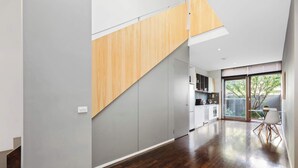 Eine moderne Küche mit grauen Schränken, einer Holztreppe und einem Essbereich mit einem Glastisch.