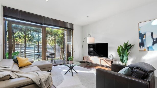 Ein modernes Wohnzimmer mit Sofa, Couchtisch, Fernseher und Essbereich.