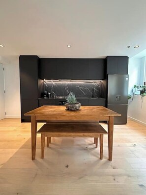 Eine moderne Küche mit dunklen Schränken, einem Holztisch und einer dekorativen Rückwand.