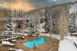 A snow-covered outdoor area with a pool, lounge chairs, and a wooden bridge. - Ski-in/out Condo with fast WiFi, grill, fireplace & shared pool, hot tubs, W/D (Vail)